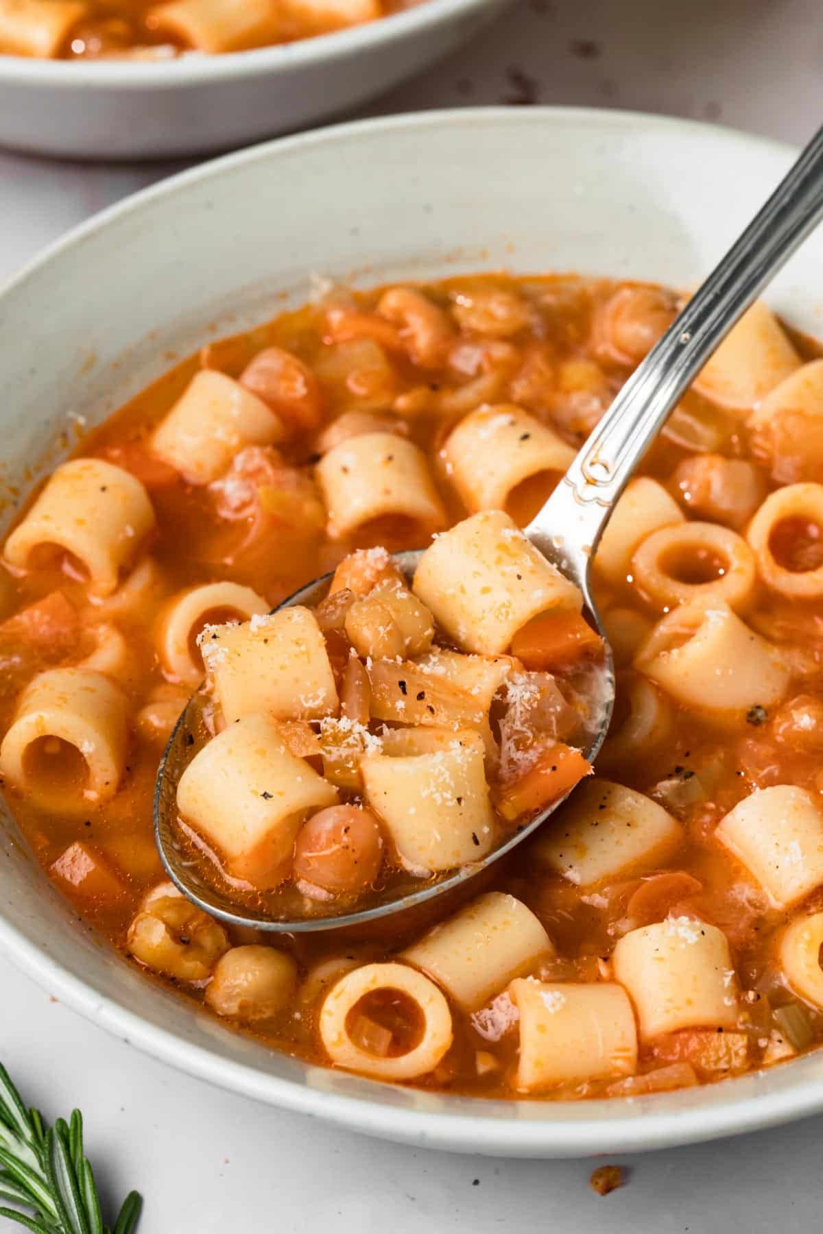 close up on a spoonful of pasta e ceci above a bowl of the soup.