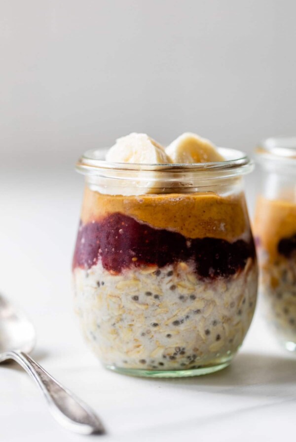 a little jar with oats, peanut butter and jelly and topped with slices of banana