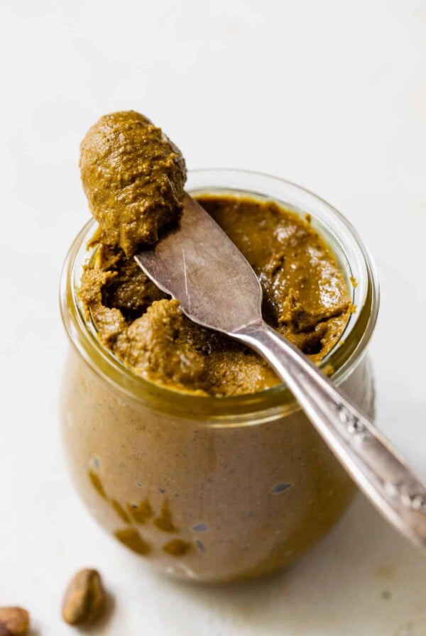 pistachio butter in a jar with a small amount on a knife