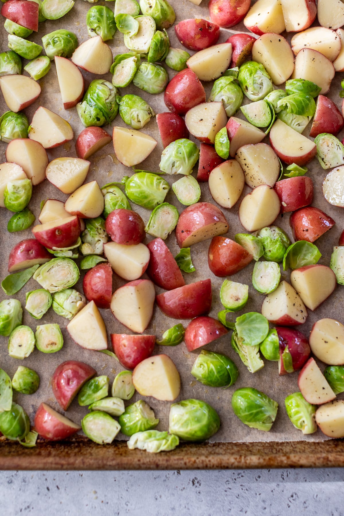chopped red potatoes and brussels sprouts on a sheet pan.