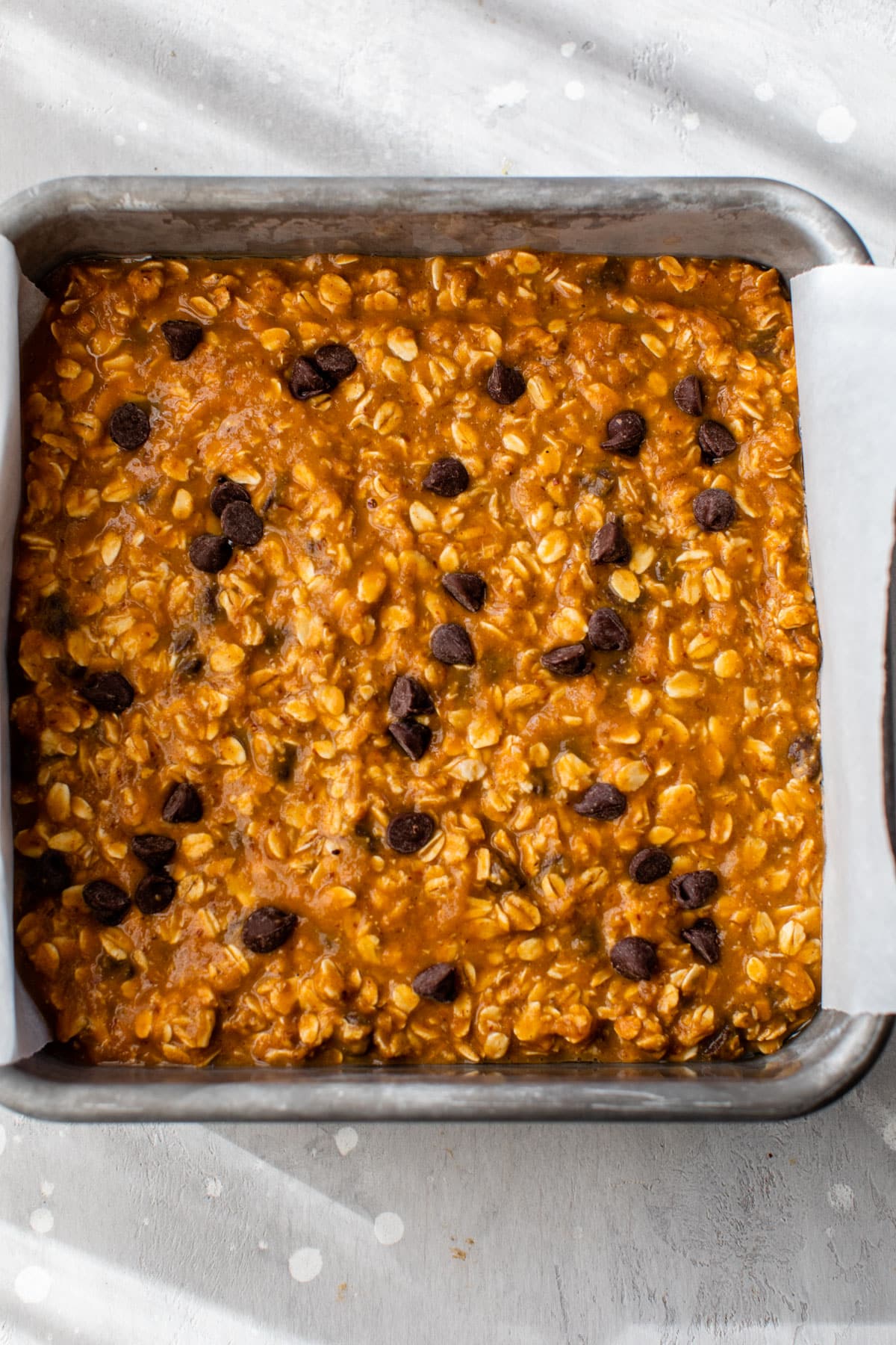 pumpkin oatmeal batter added to a parchment paper lined baking dish