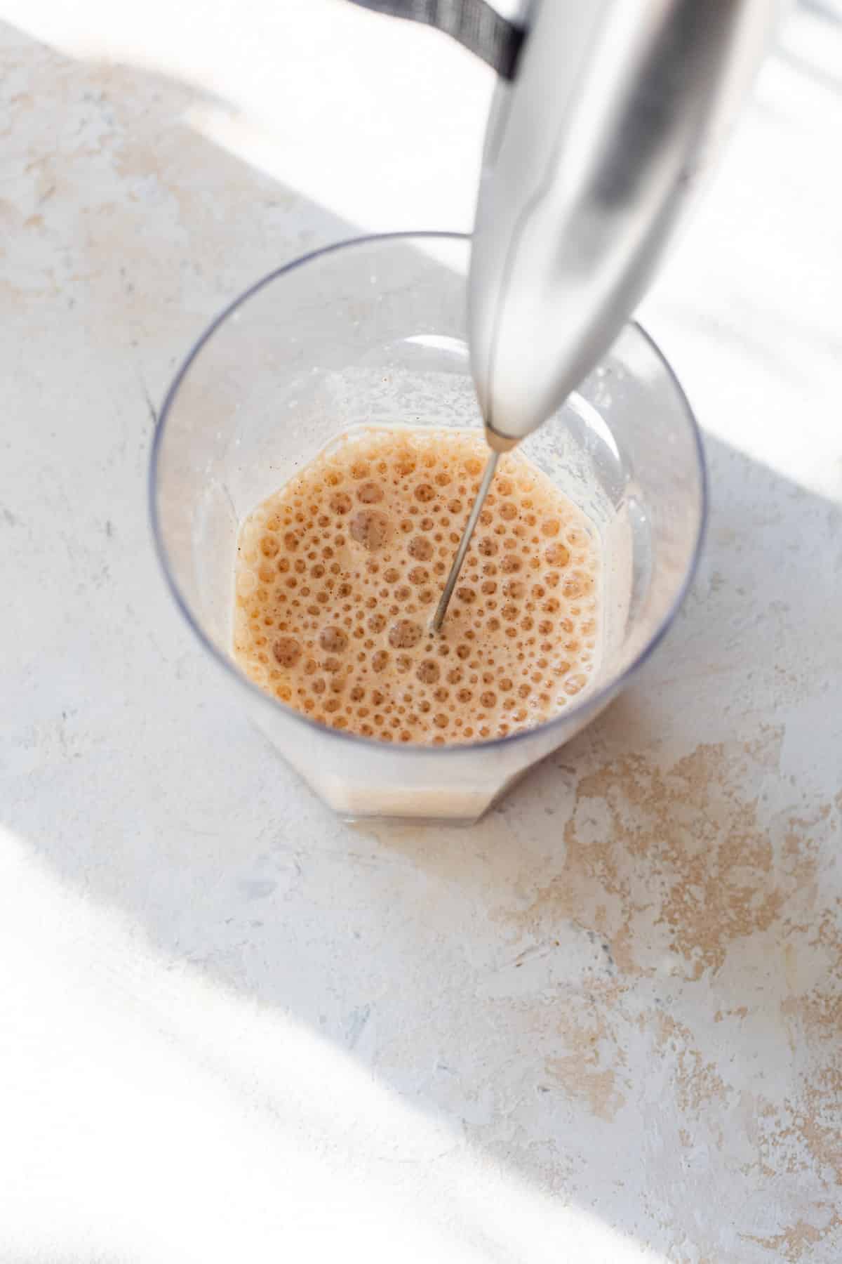 using a milk frother to make frothy pumpkin creamer in a glass.