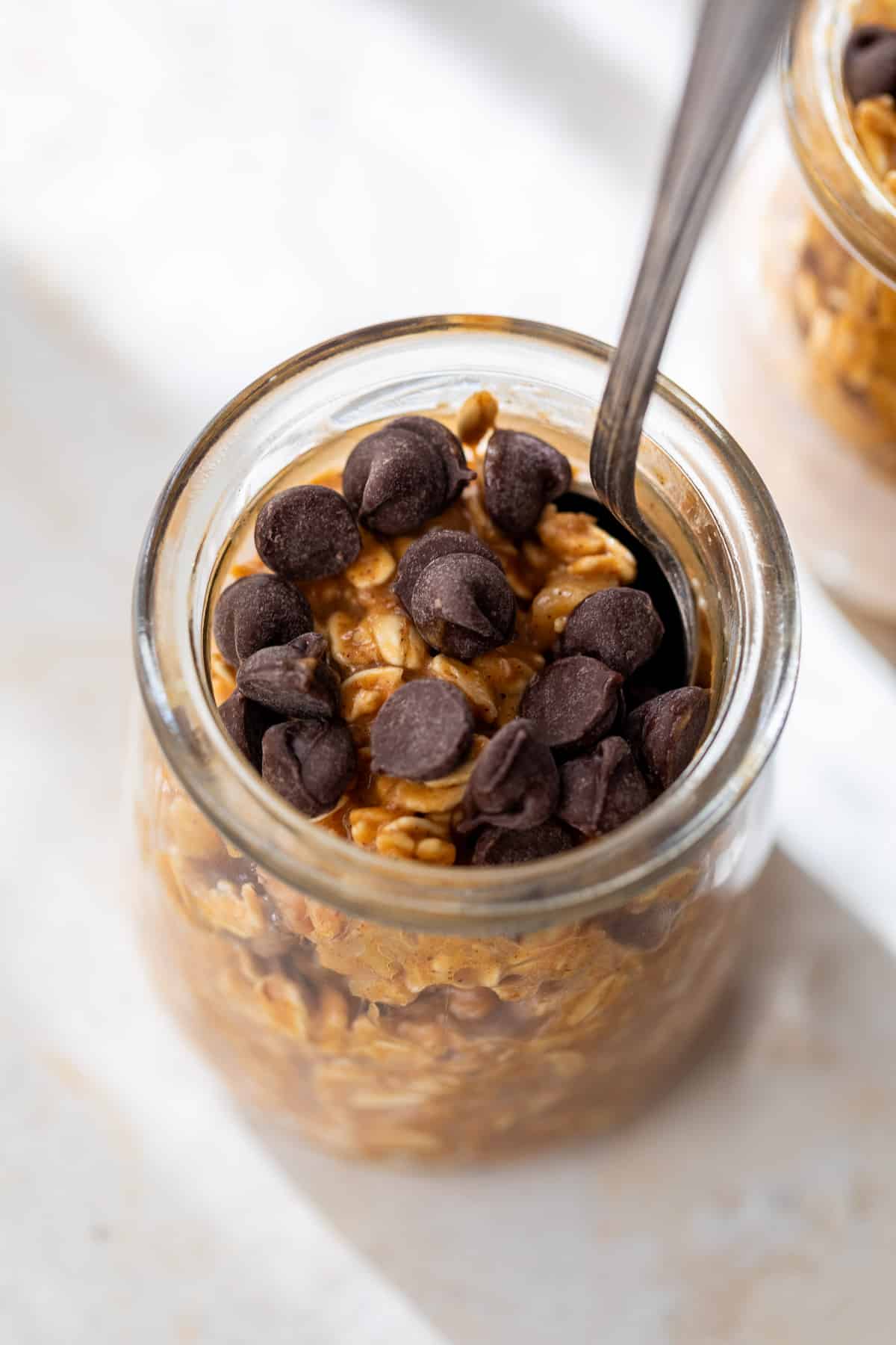 close up on pumpkin overnight oats topped with chocolate chips in a glass jar.
