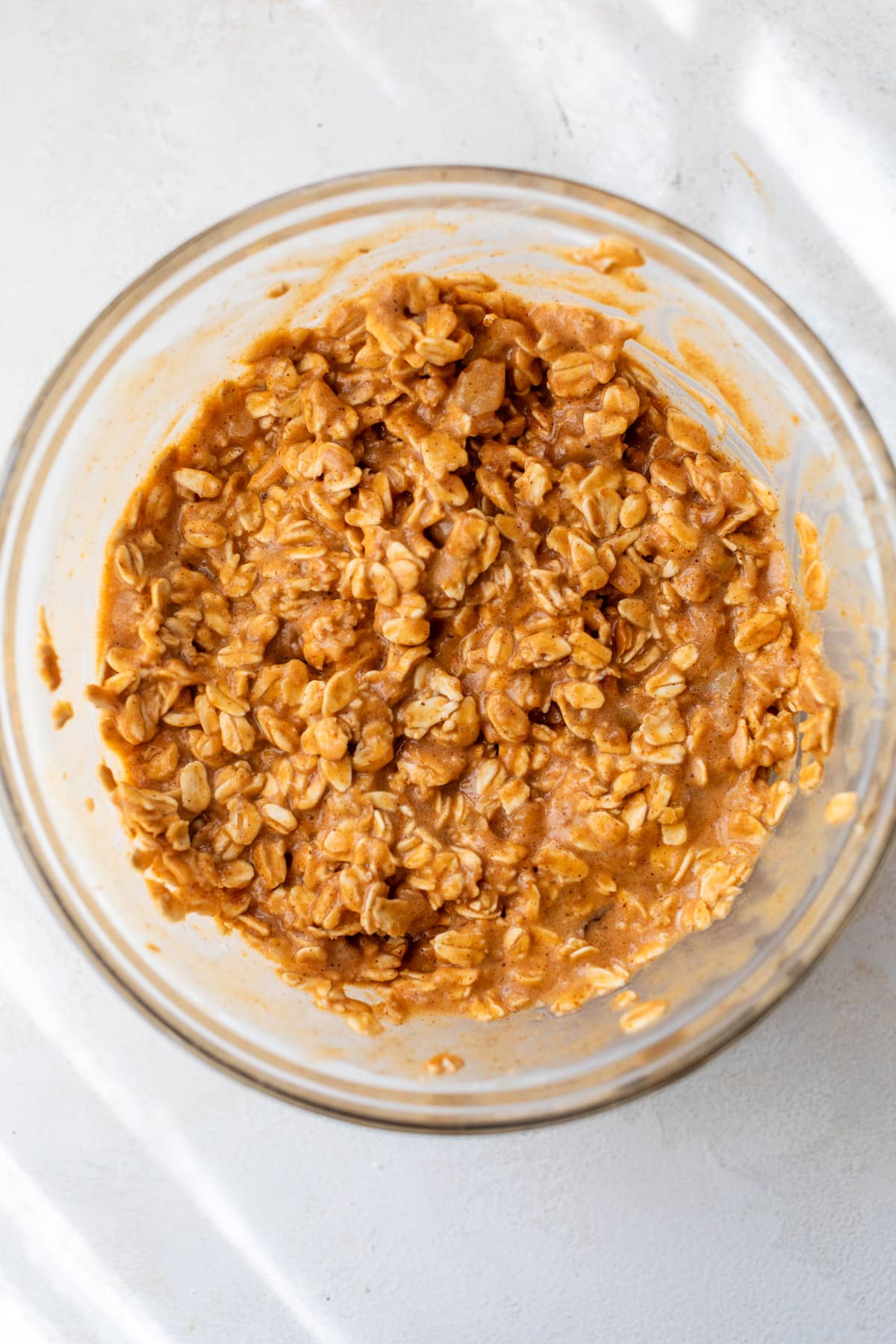 overhead view of oats mixed with pumpkin milk in a large glass bowl.