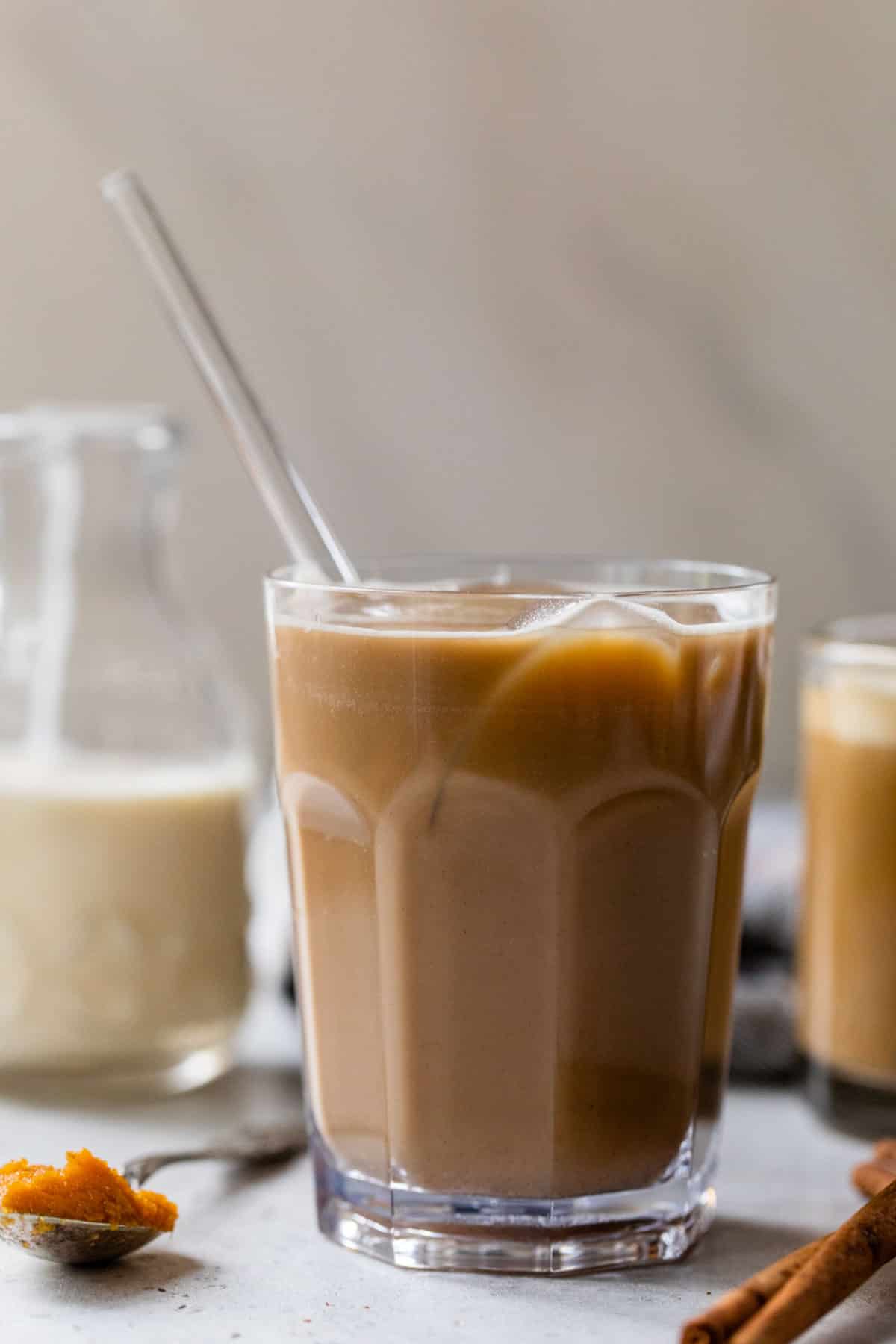 side view of an iced pumpkin spice latte with a straw