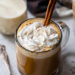 pumpkin spice latte in a glass with whipped cream and a cinnamon stick