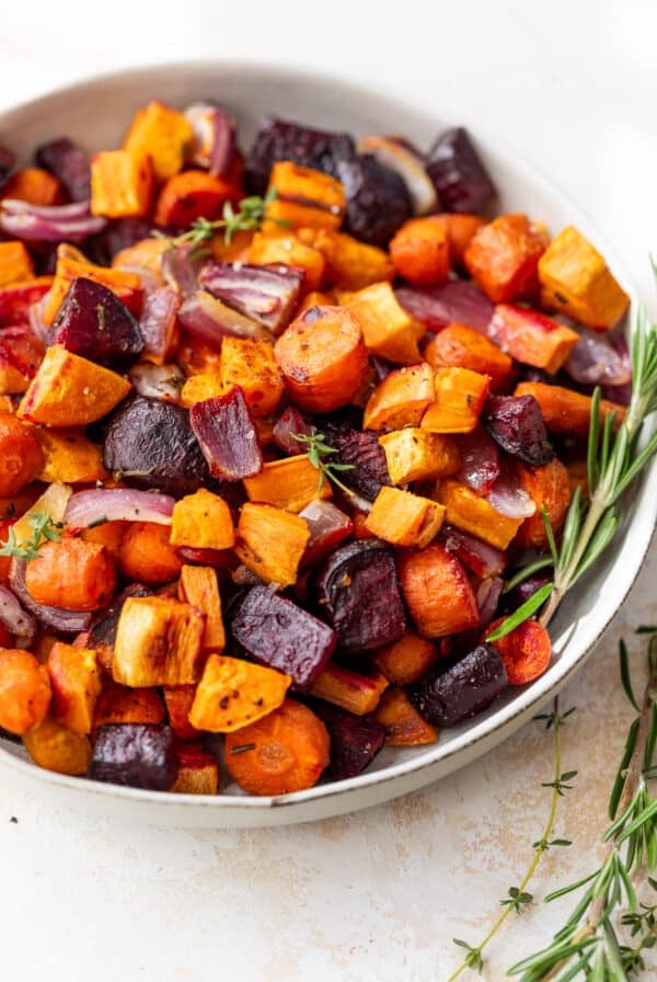a medley of roasted root vegetables in a large white bowl.