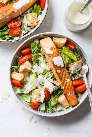 bowl of lettuce topped with grape tomatoes and cooked salmon