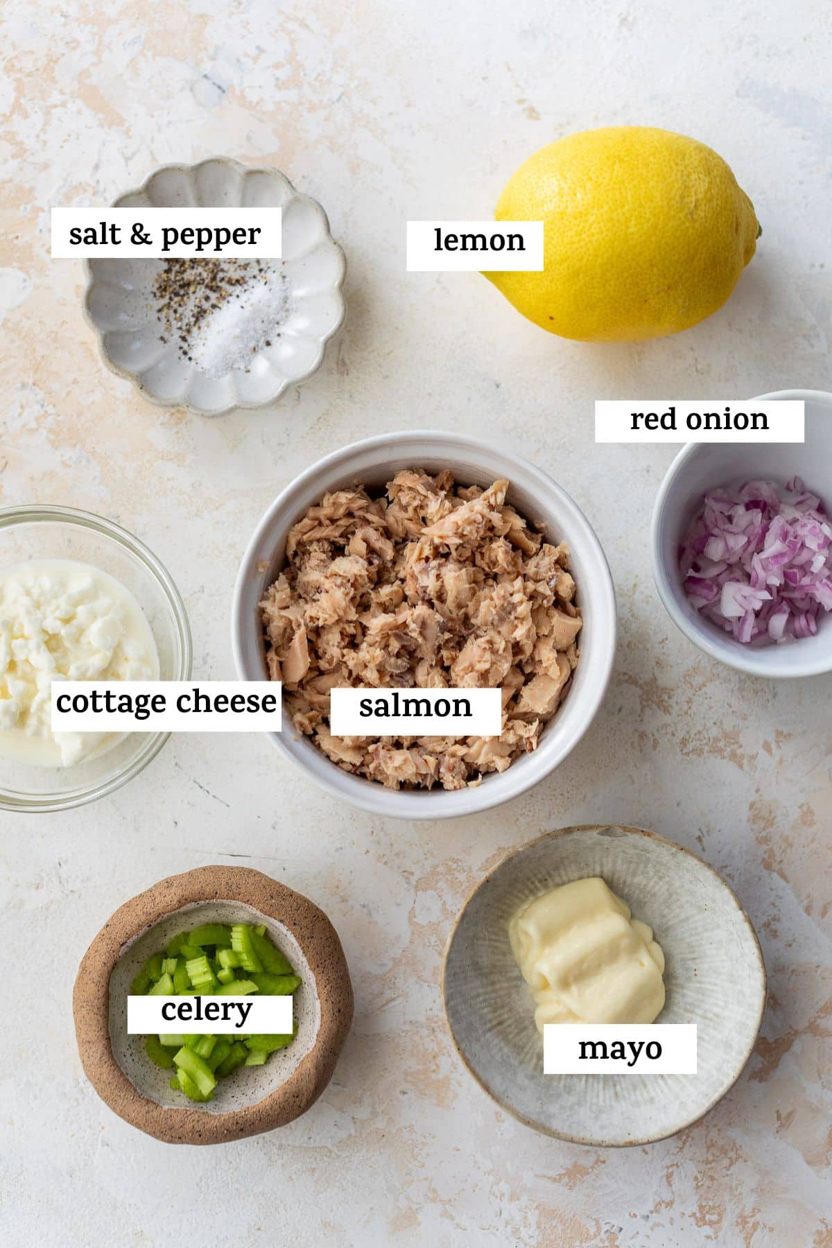 ingredients for salmon salad in individual bowls with labels.