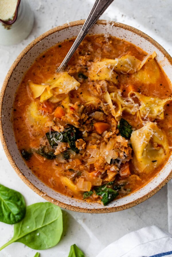 overview of sausage tortellini soup in a bowl with a spoon