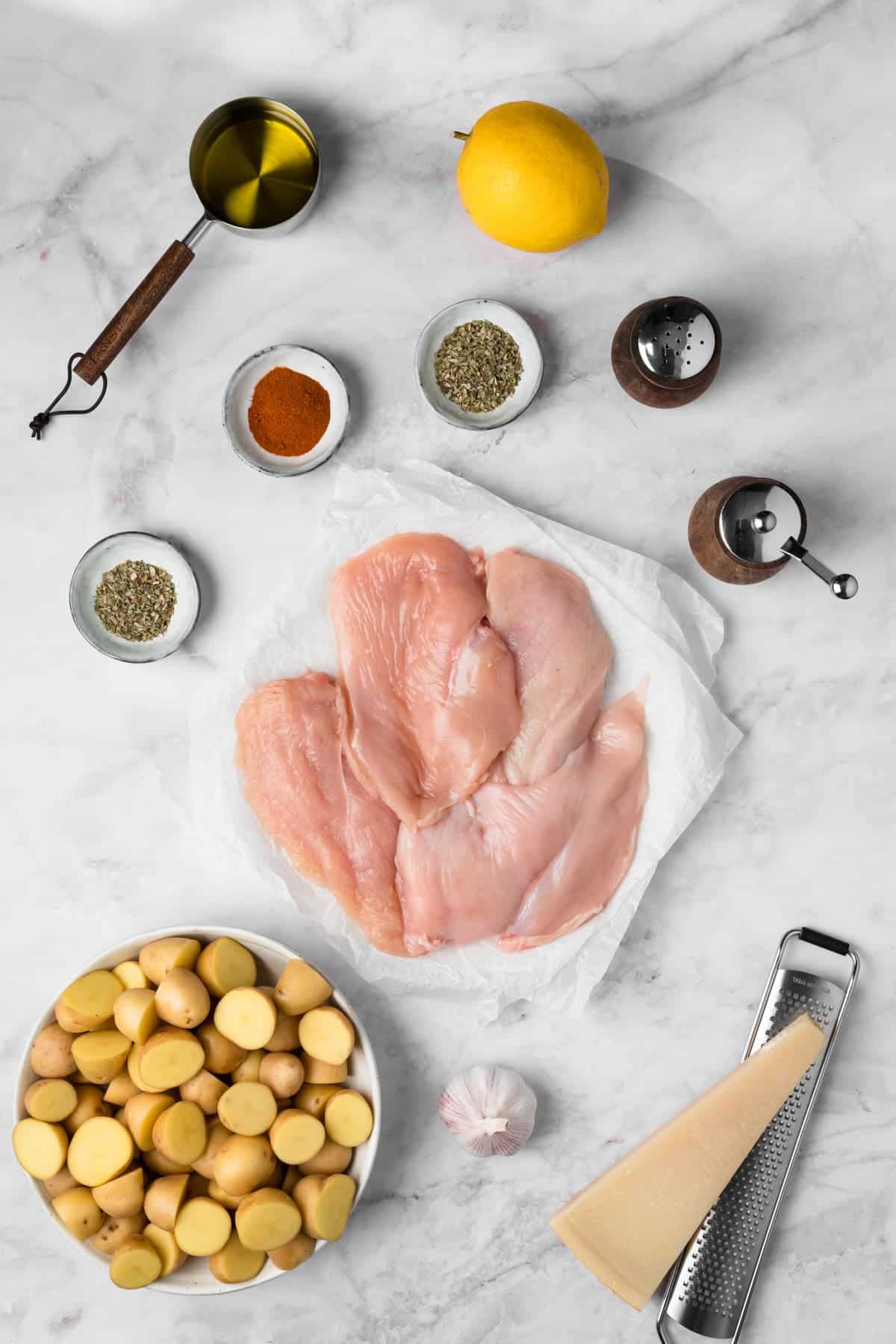 Overhead view of the ingredients for sheet pan chicken and potatoes in individual bowls.