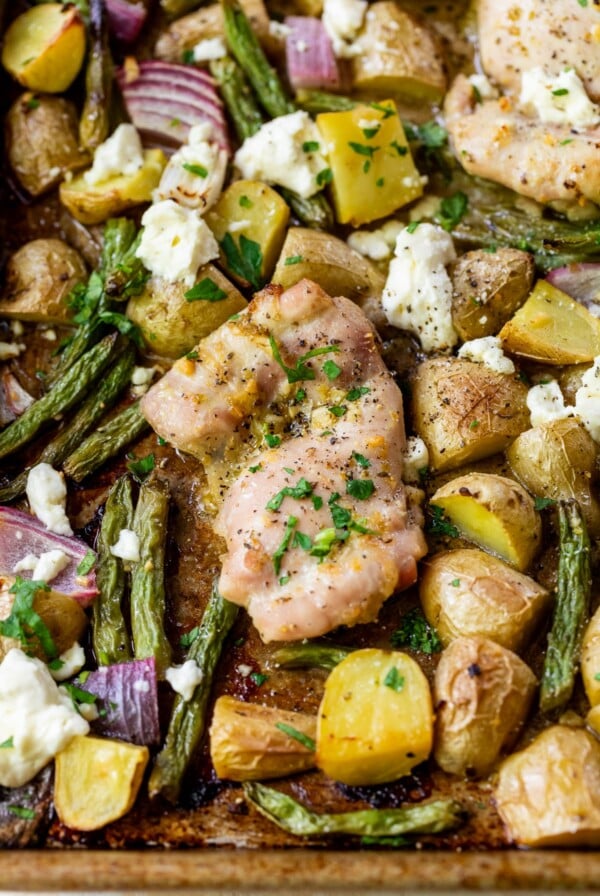 close up on cooked vegetables and chicken thighs on a sheet pan.