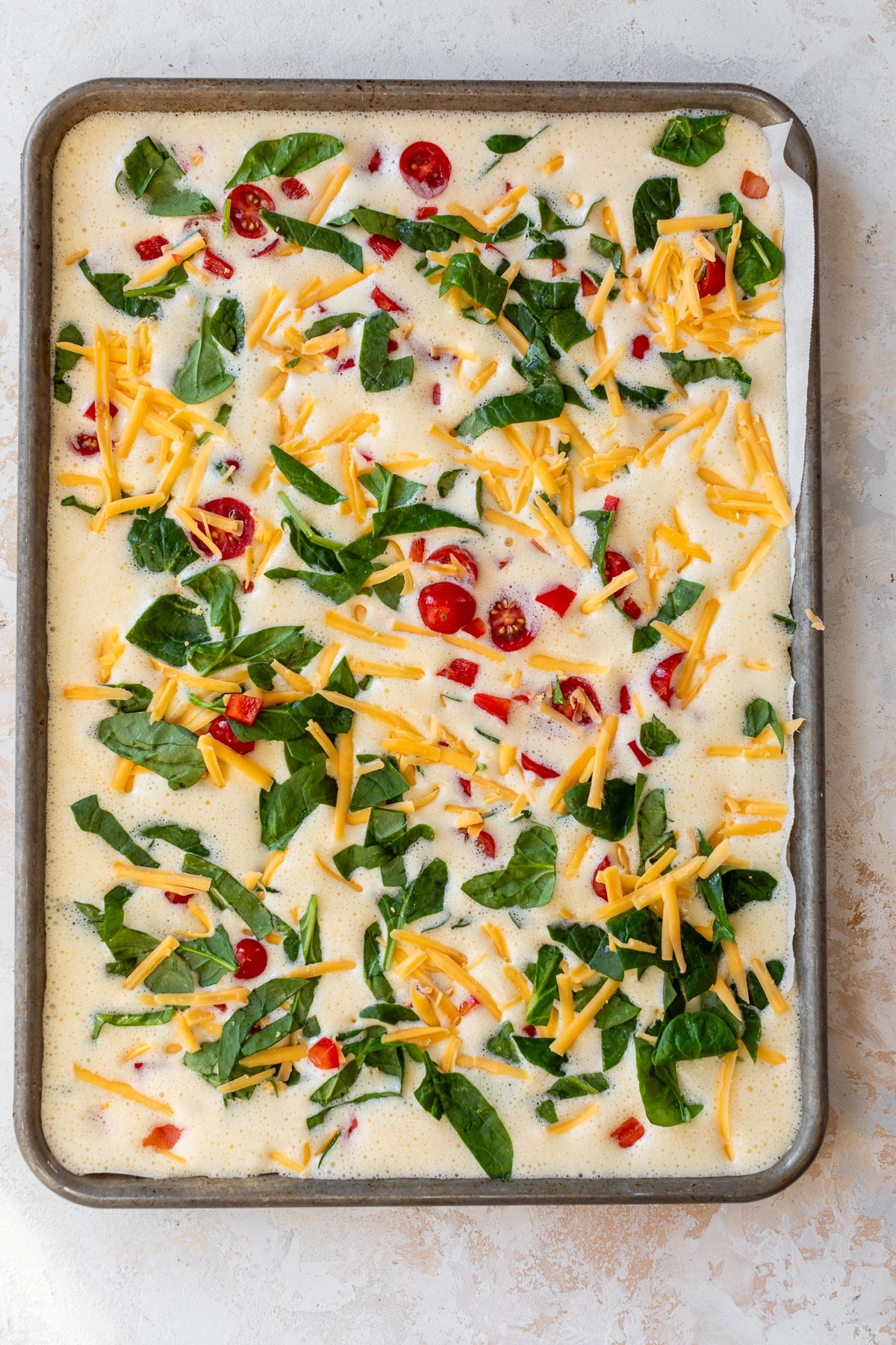 sheet pan eggs poured into a baking sheet before cooking