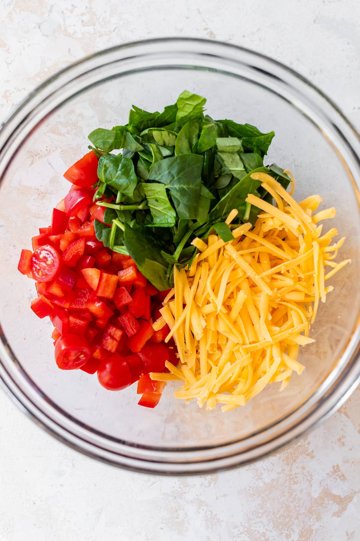 veggies and shredded cheese in a glass bowl