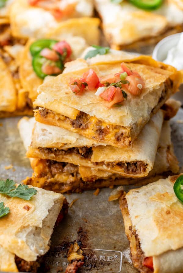 close up on a stack of sheet pan quesadillas topped with salsa.