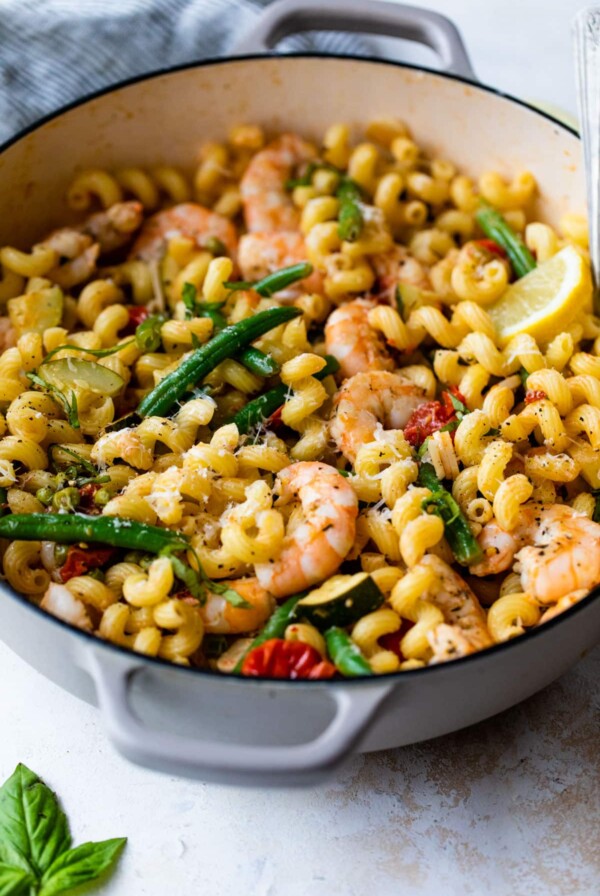 side view of shrimp primavera in a dutch oven with a spoon