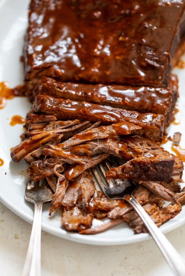 slow cooker beef brisket sliced on a plate with forks