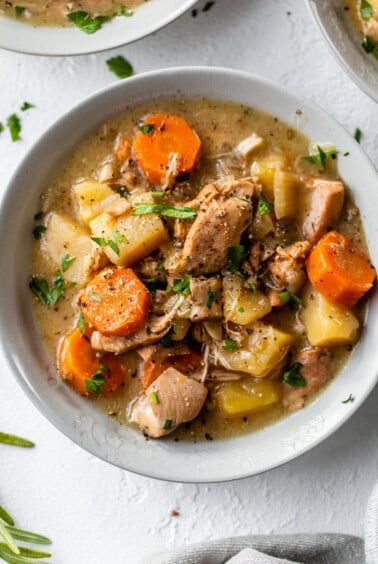 a bowl of stew with chicken, potatoes and carrots