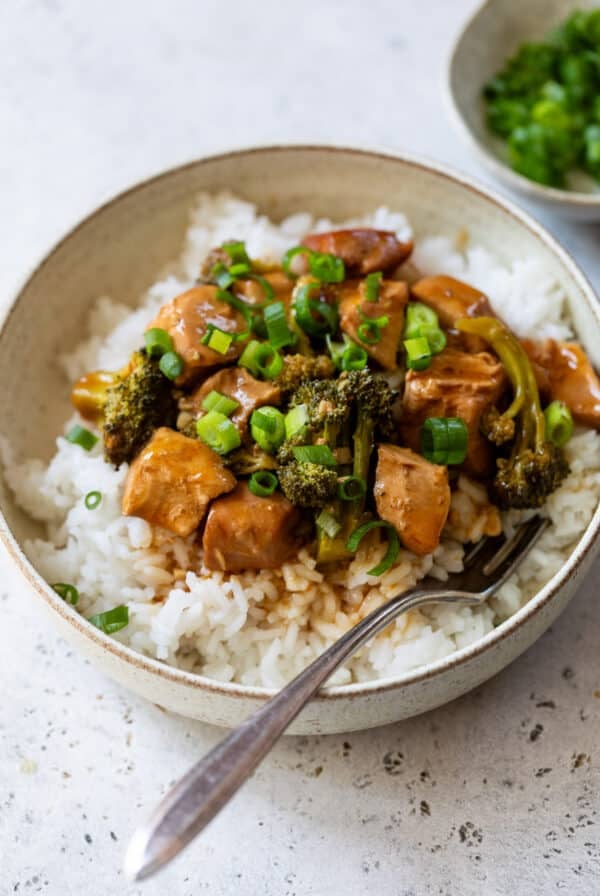 orange chicken and broccoli topped on a bed of white rice in a bowl.