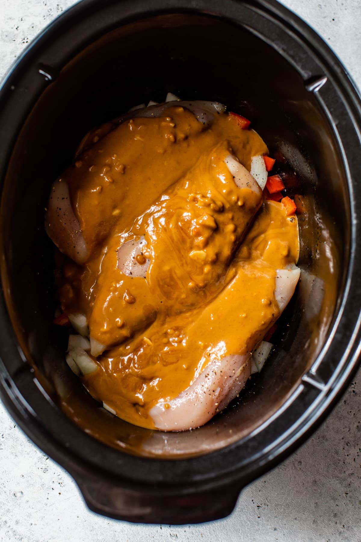 chicken breast and sauce inside of a slow cooker