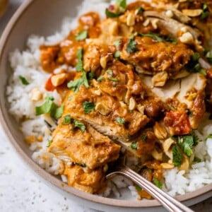 slow cooker peanut chicken on top of rice on a plate with a fork