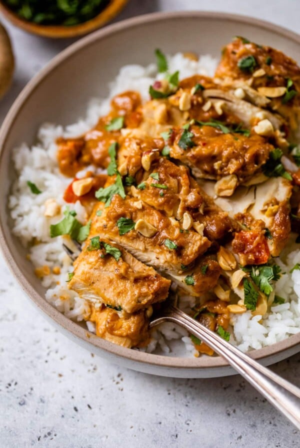 slow cooker peanut chicken on top of rice on a plate with a fork