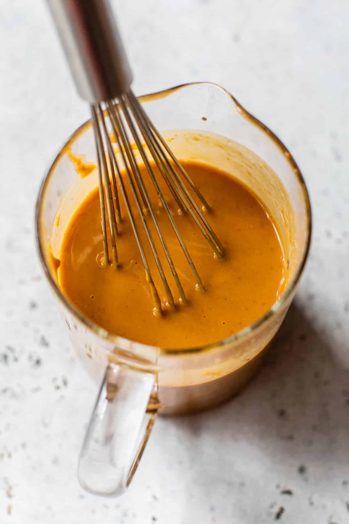 sauce ingredients in a glass measuring cup with a whisk
