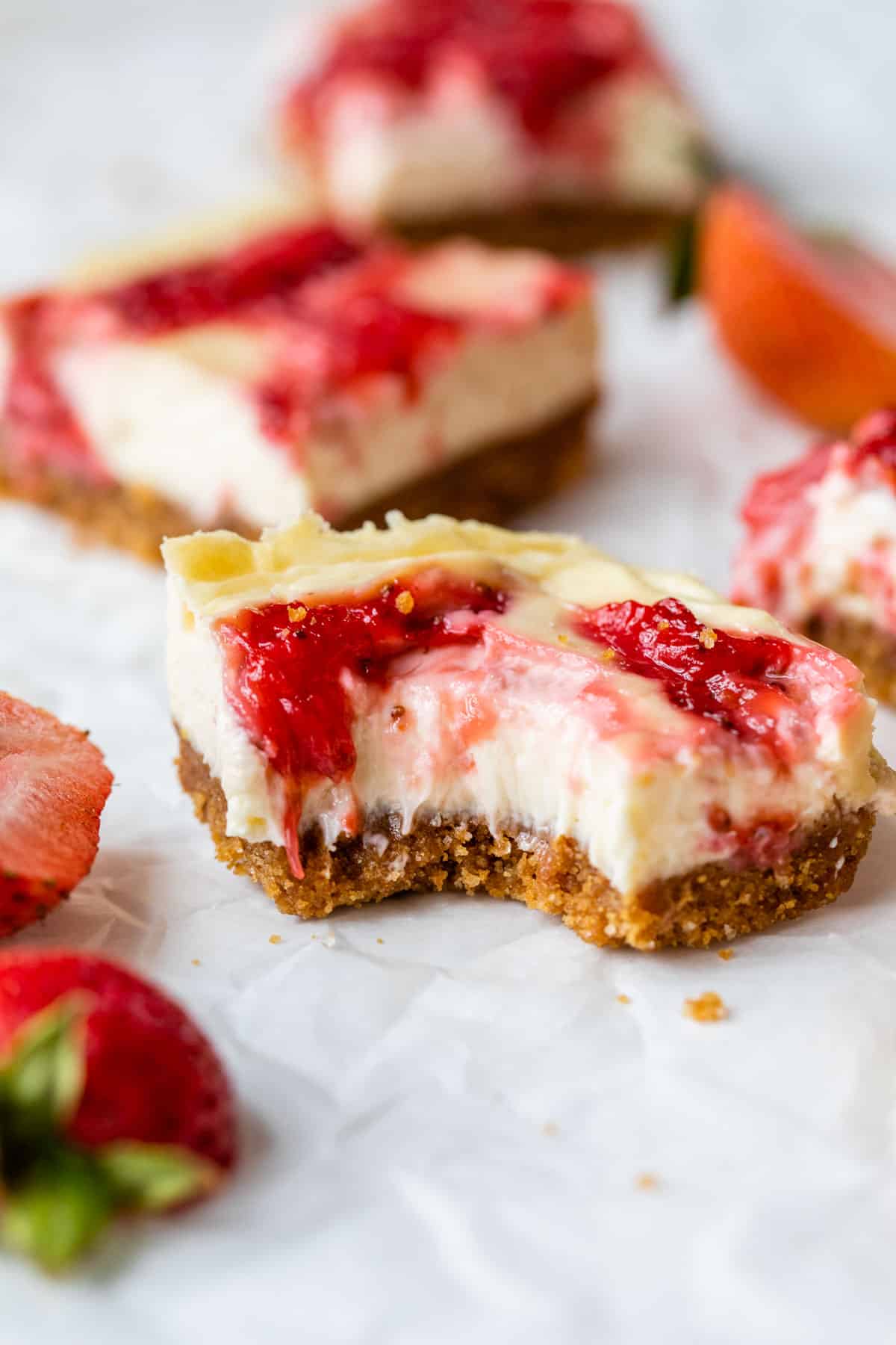 cheesecake bar with a bite taken out of it beside a few fresh strawberries