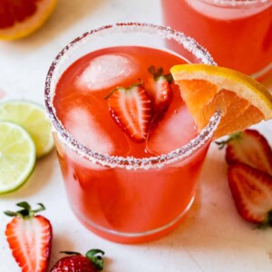 a strawberry ginger paloma in a sugar lined glass with a strawberry inside
