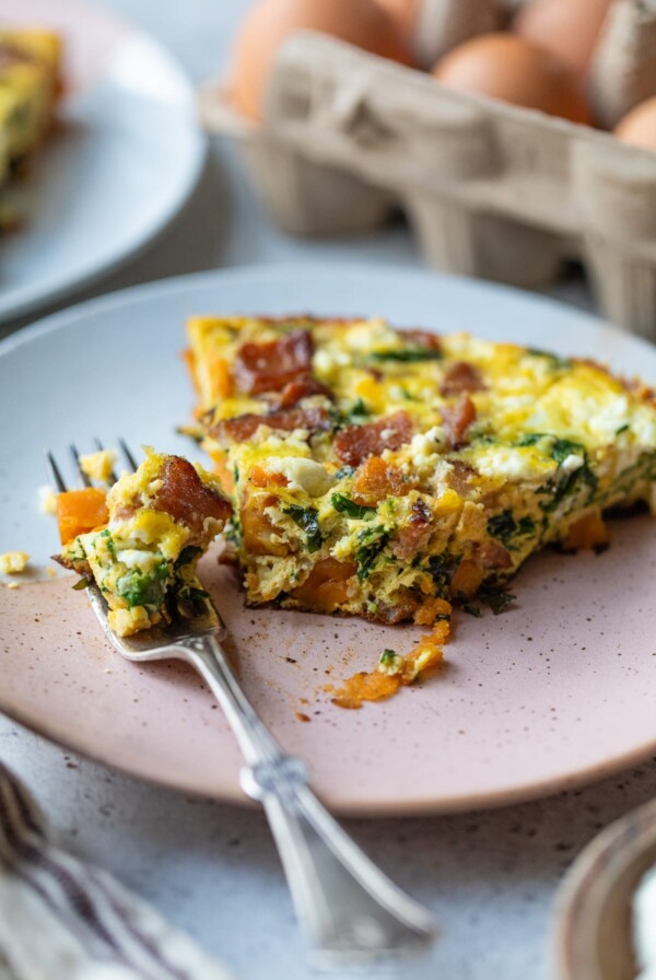 slice of sweet potato frittata on a plate with a bite taken out
