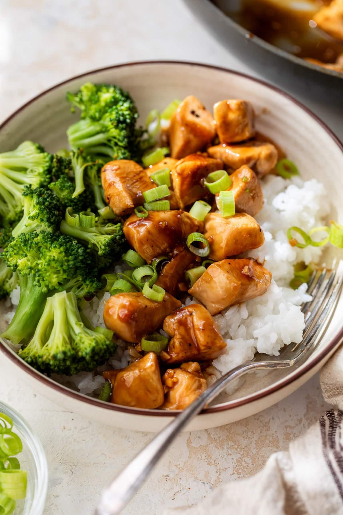 teriyaki chicken and broccoli served over white rice in a bowl.