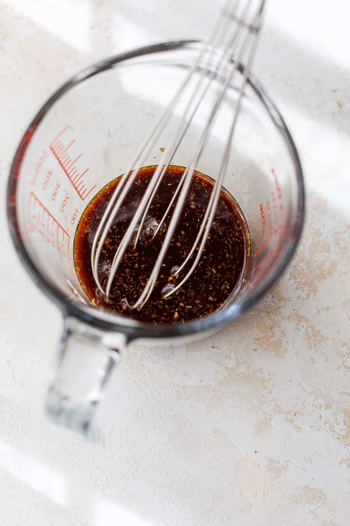 whisking homemade teriyaki sauce in a glass measuring cup.