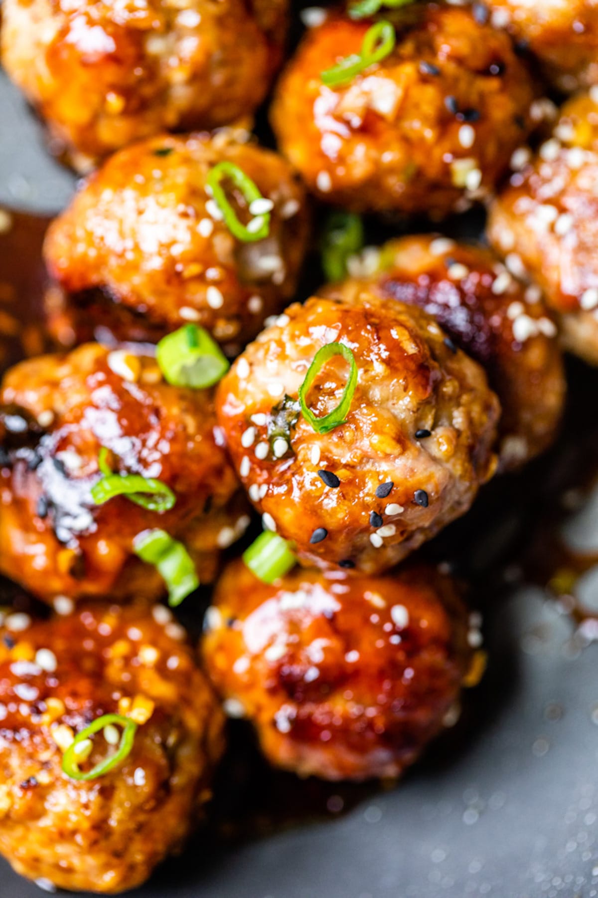 close up of pork meatballs topped with sesame seeds and green onions