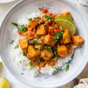 white rice topped with tofu curry in a white bowl.