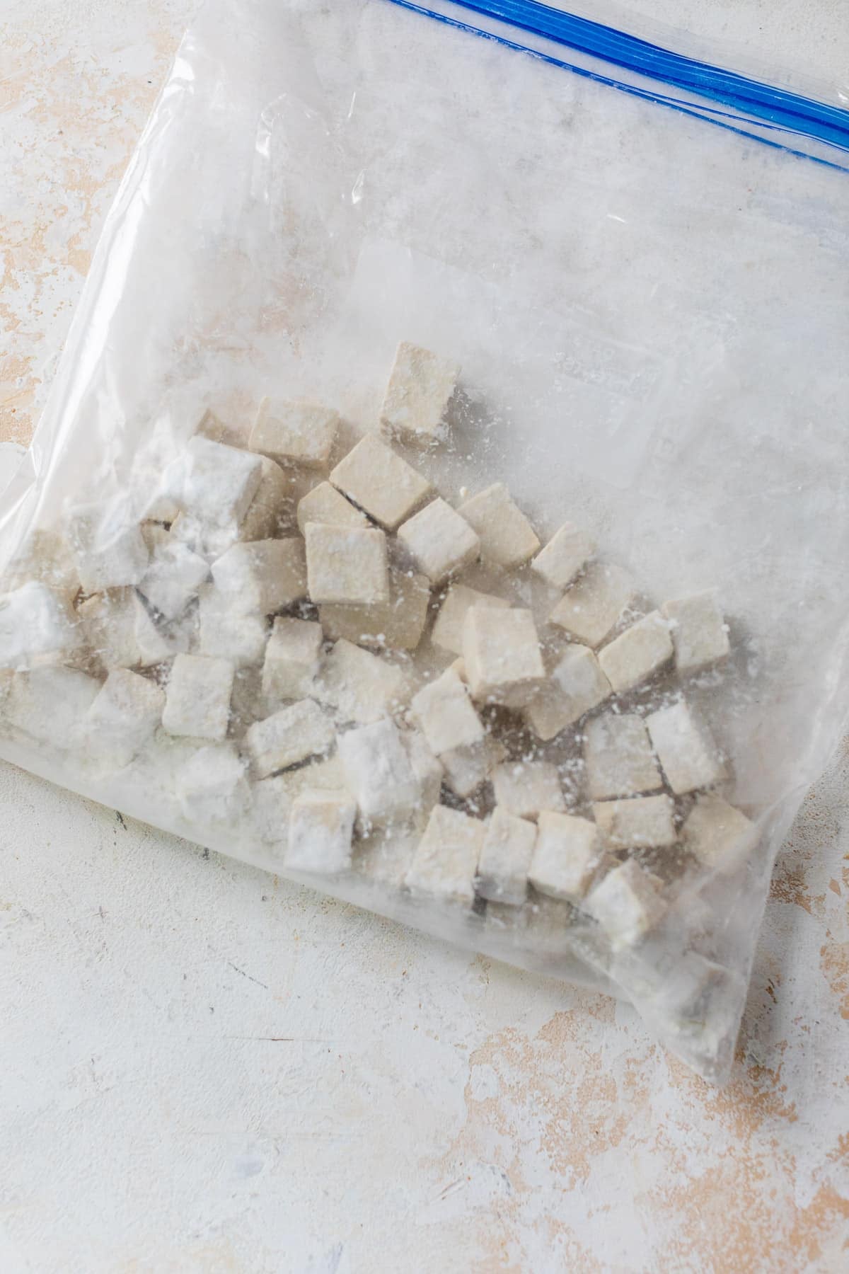 tofu cubes and cornstarch being tossed together in a large ziplock bag.