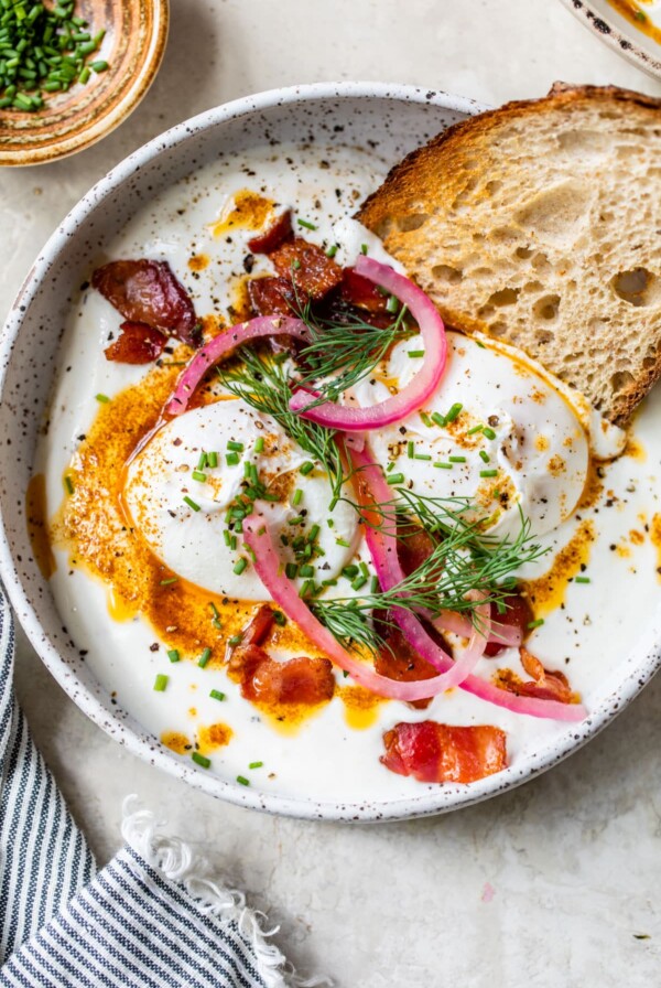 Greek yogurt topped with poached eggs, pickled red onion and bacon