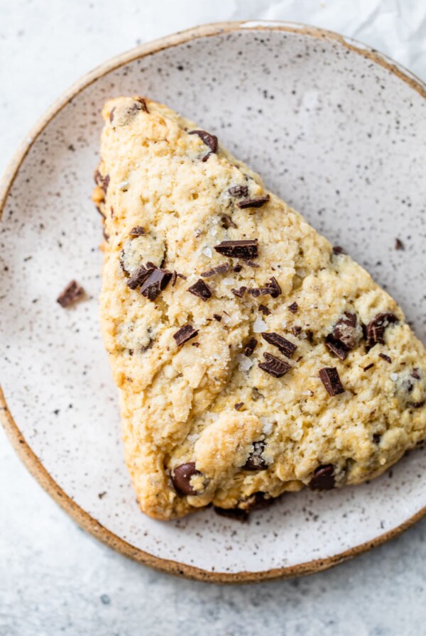 a scone on a plate topped with chopped chocolate