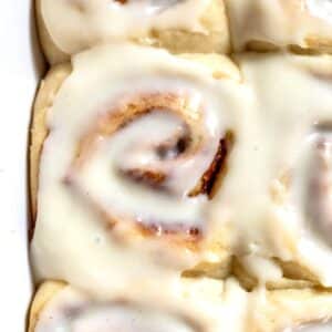 close up on a cream cheese frosting-topped vegan cinnamon roll.