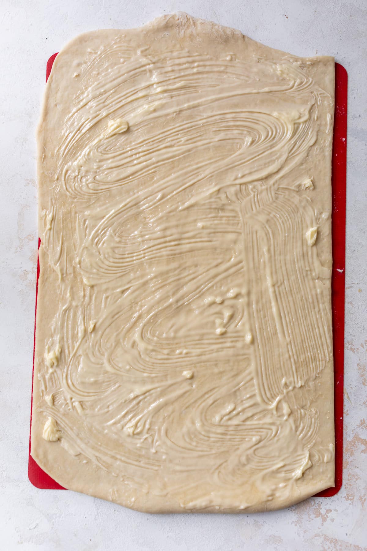 overhead view of a rectangle of vegan cinnamon roll dough slathered with butter.