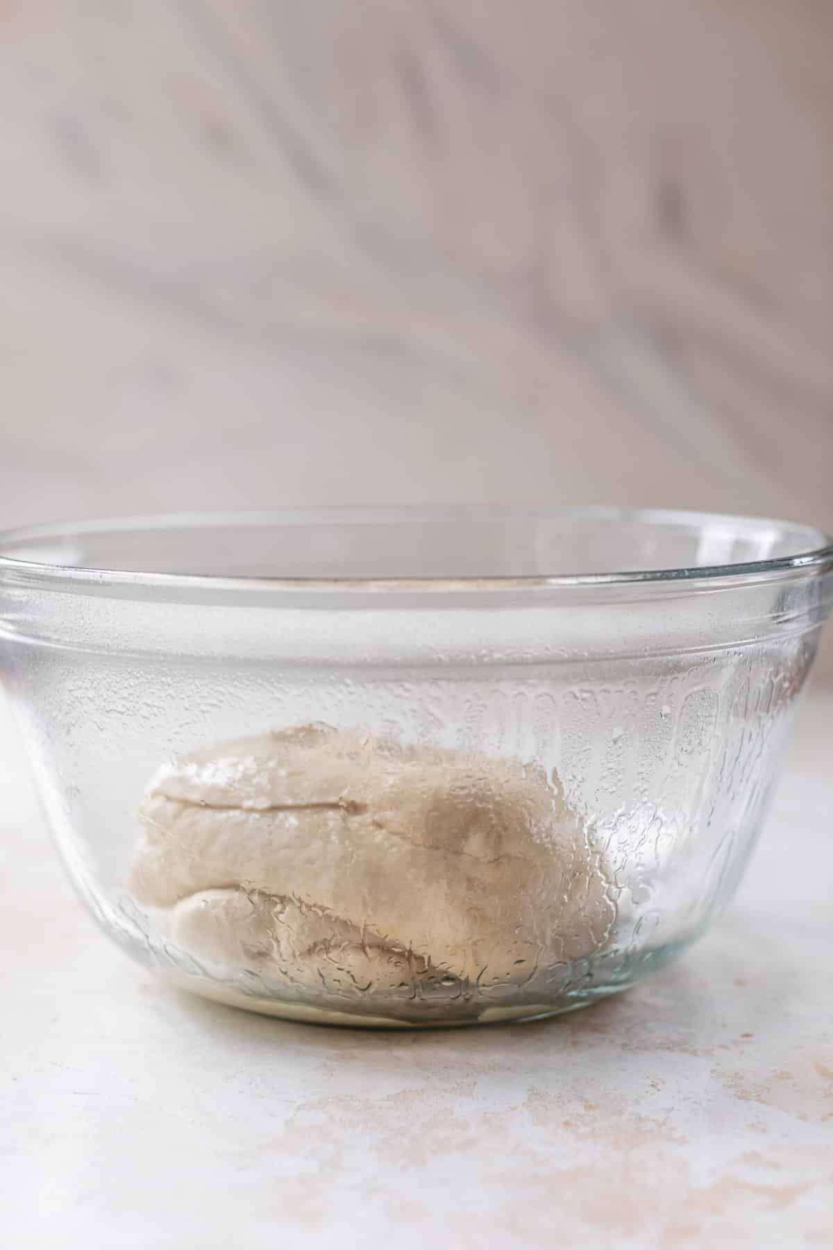 side view of vegan cinnamon roll dough in a glass bowl.