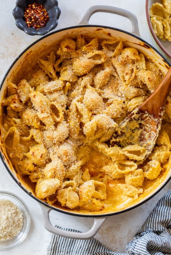 overhead view of a wooden spoon scooping vegan mac and cheese from a large pot.