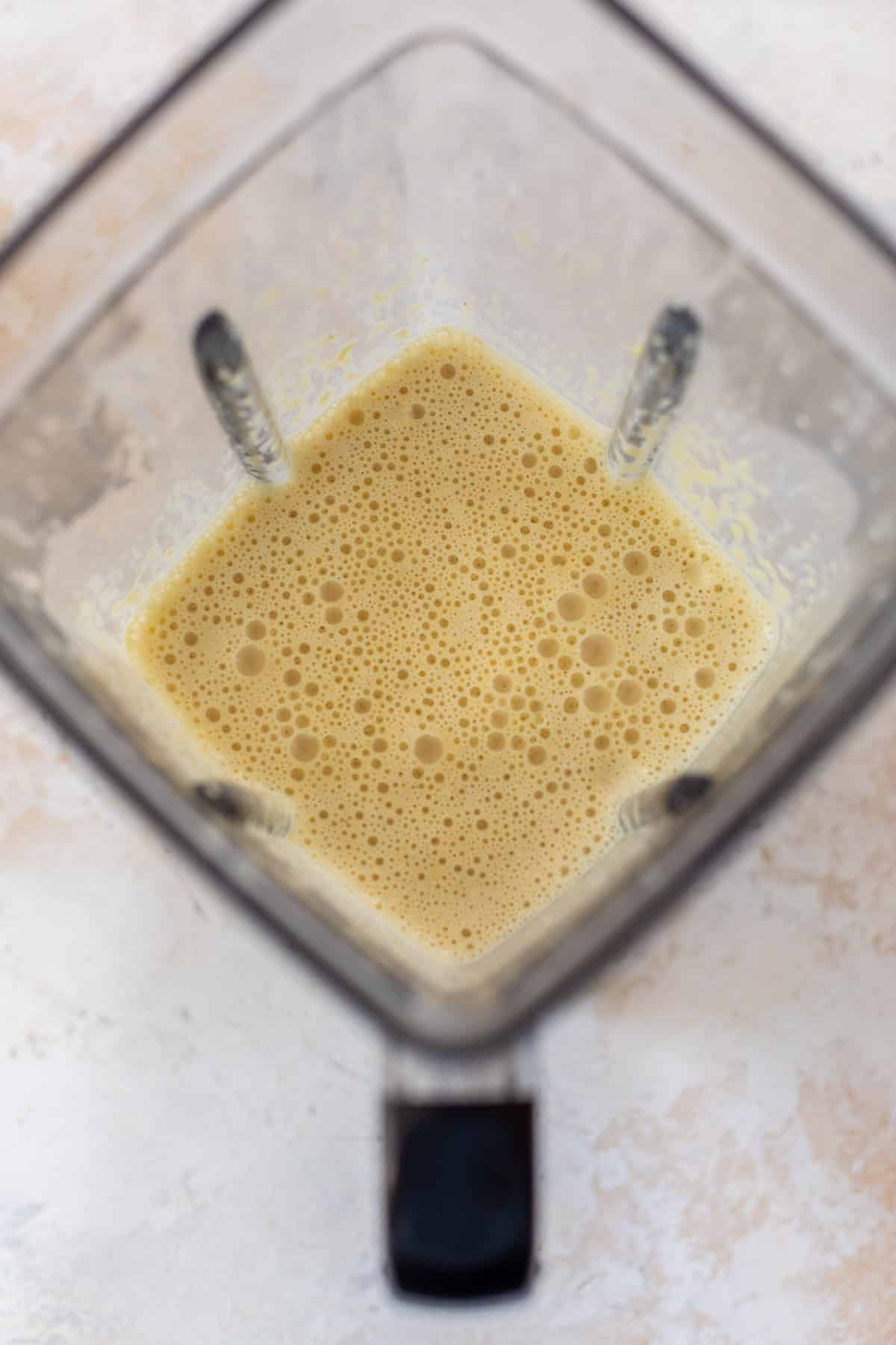overhead view of a bubbly vegan mac and cheese sauce in a large blender.