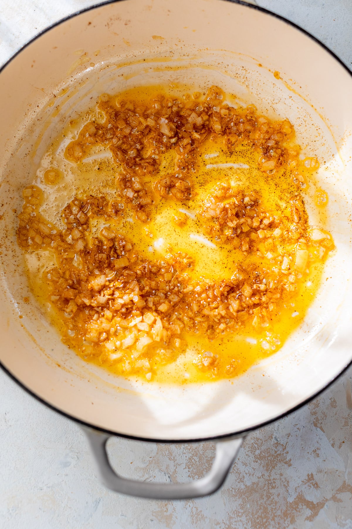 overhead view of chopped onions sautéing in a large pot for vegan mac and cheese.