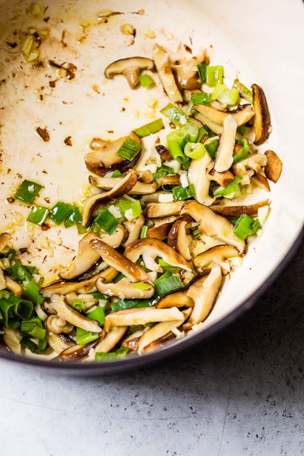 cooking mushrooms and green onions in a large pot.