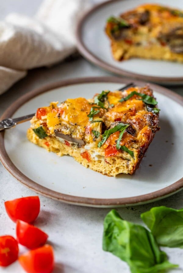 a slice of a crustless vegetable quiche on a white plate.
