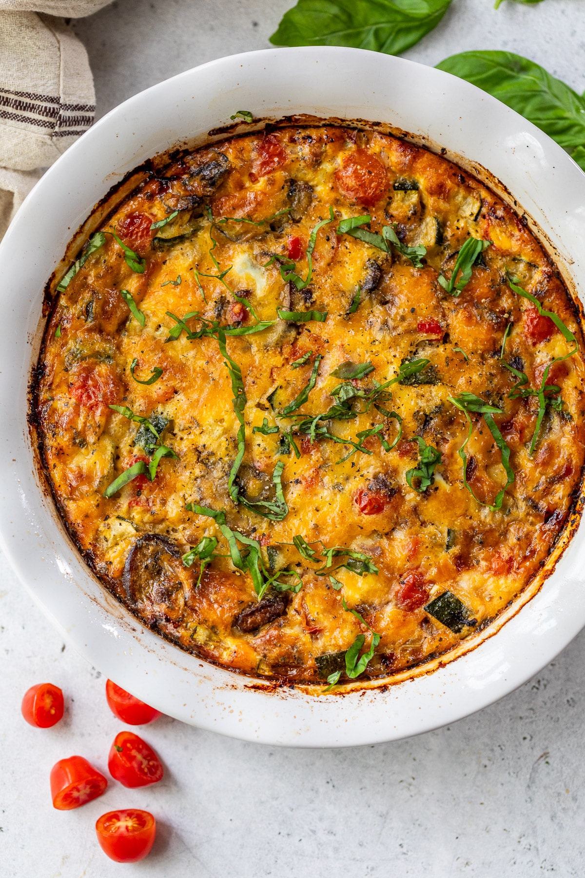 a baked crustless vegetable quiche in a large white pie plate.