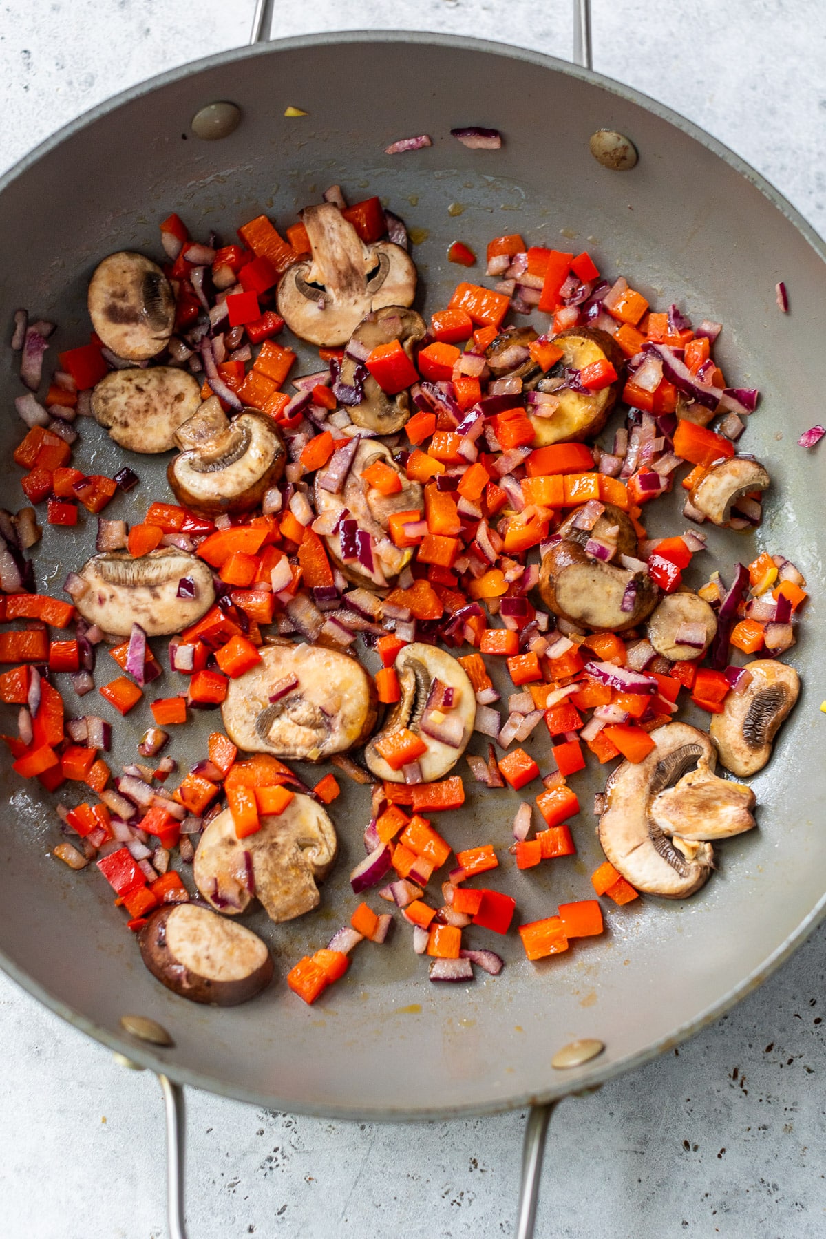 cooking diced peppers, onions, and mushrooms in a large skillet.