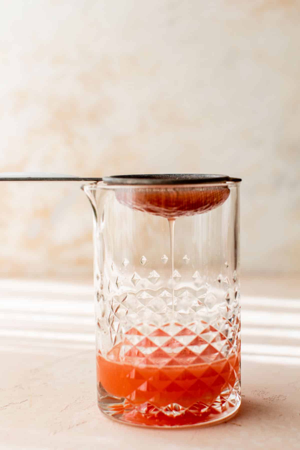 watermelon margarita being strained into a glass